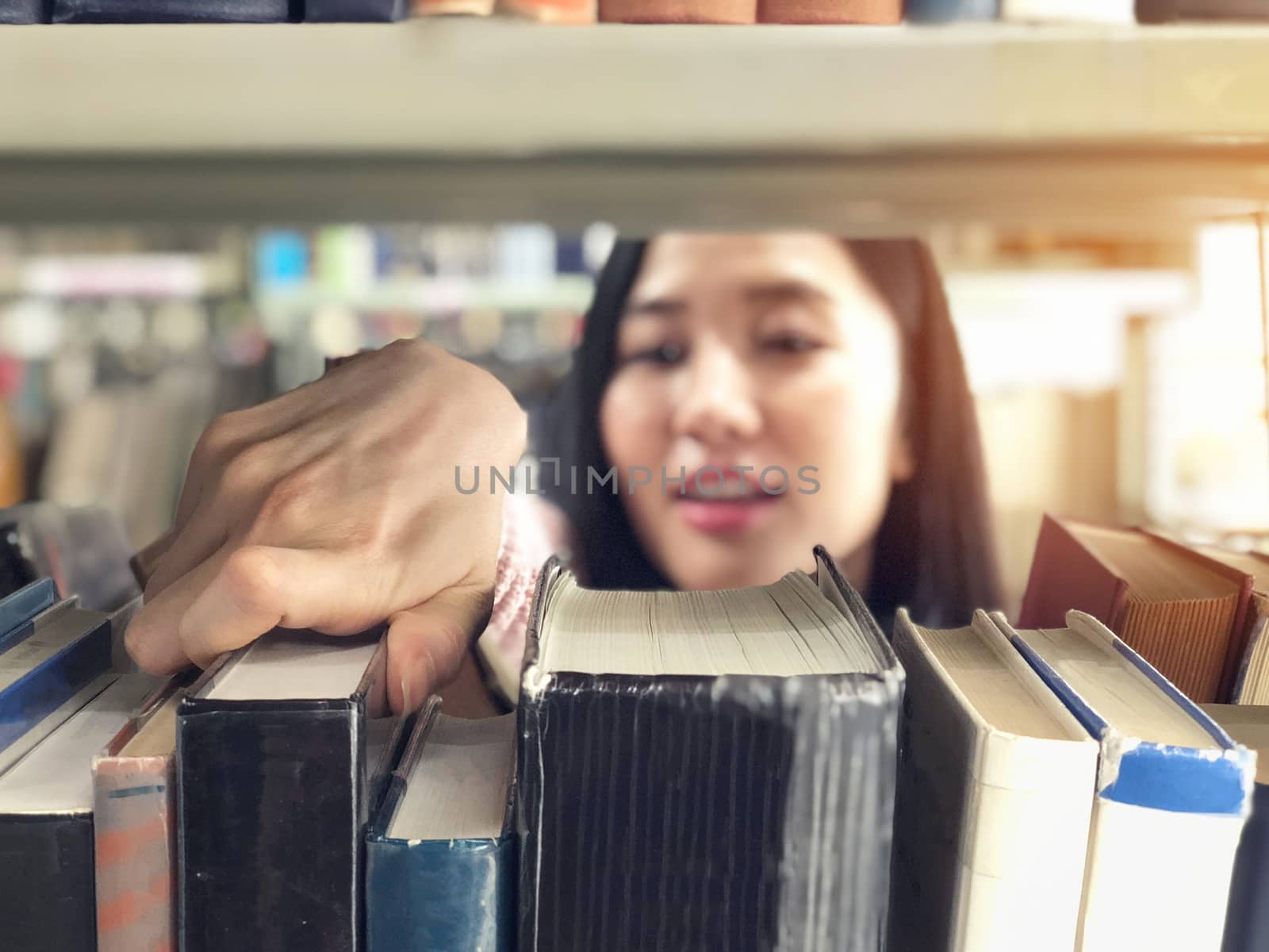 Young woman picking a book off the shelf in a library