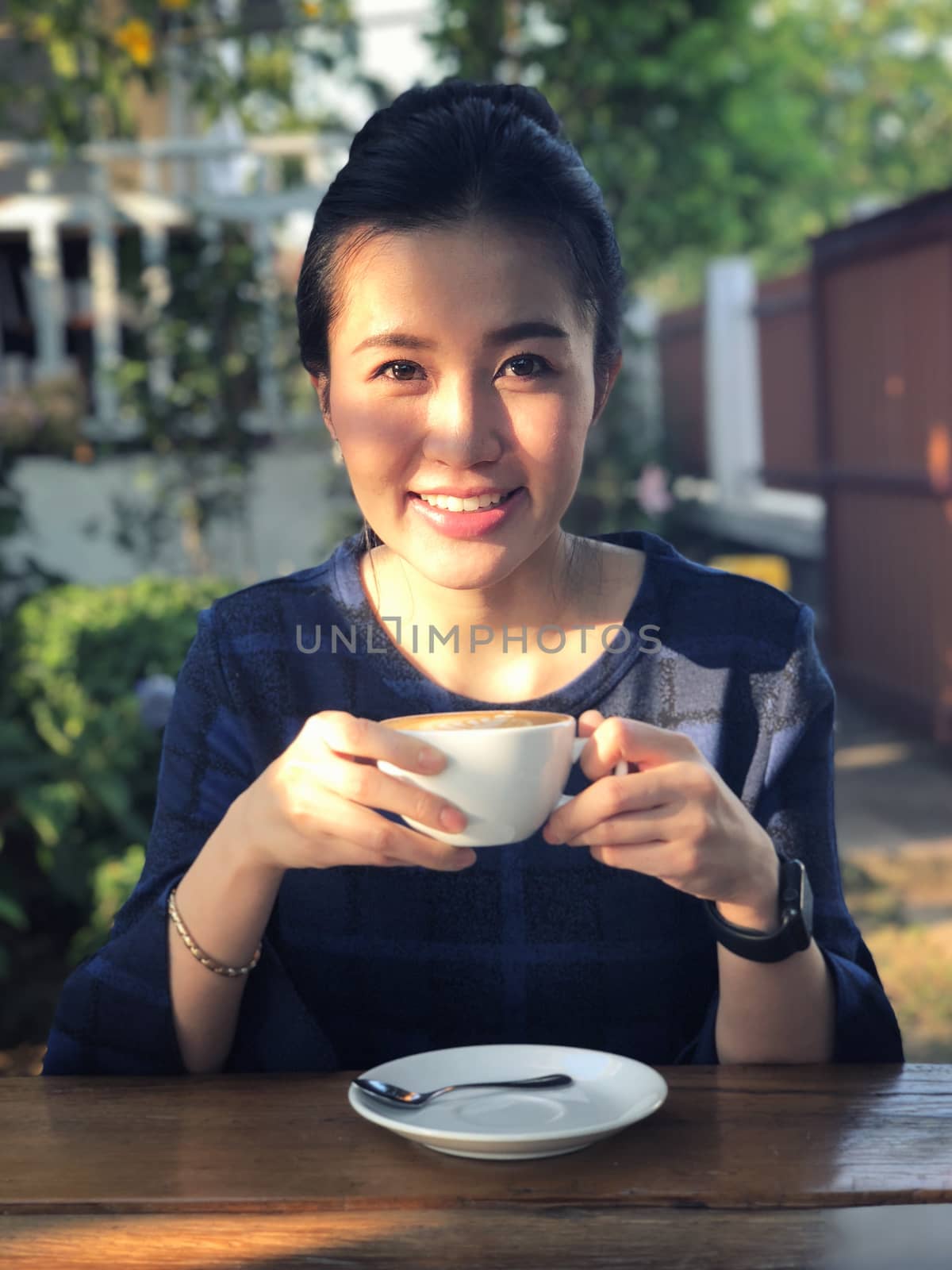 Young woman drinking coffee in in sunshine light enjoying her morning coffee.