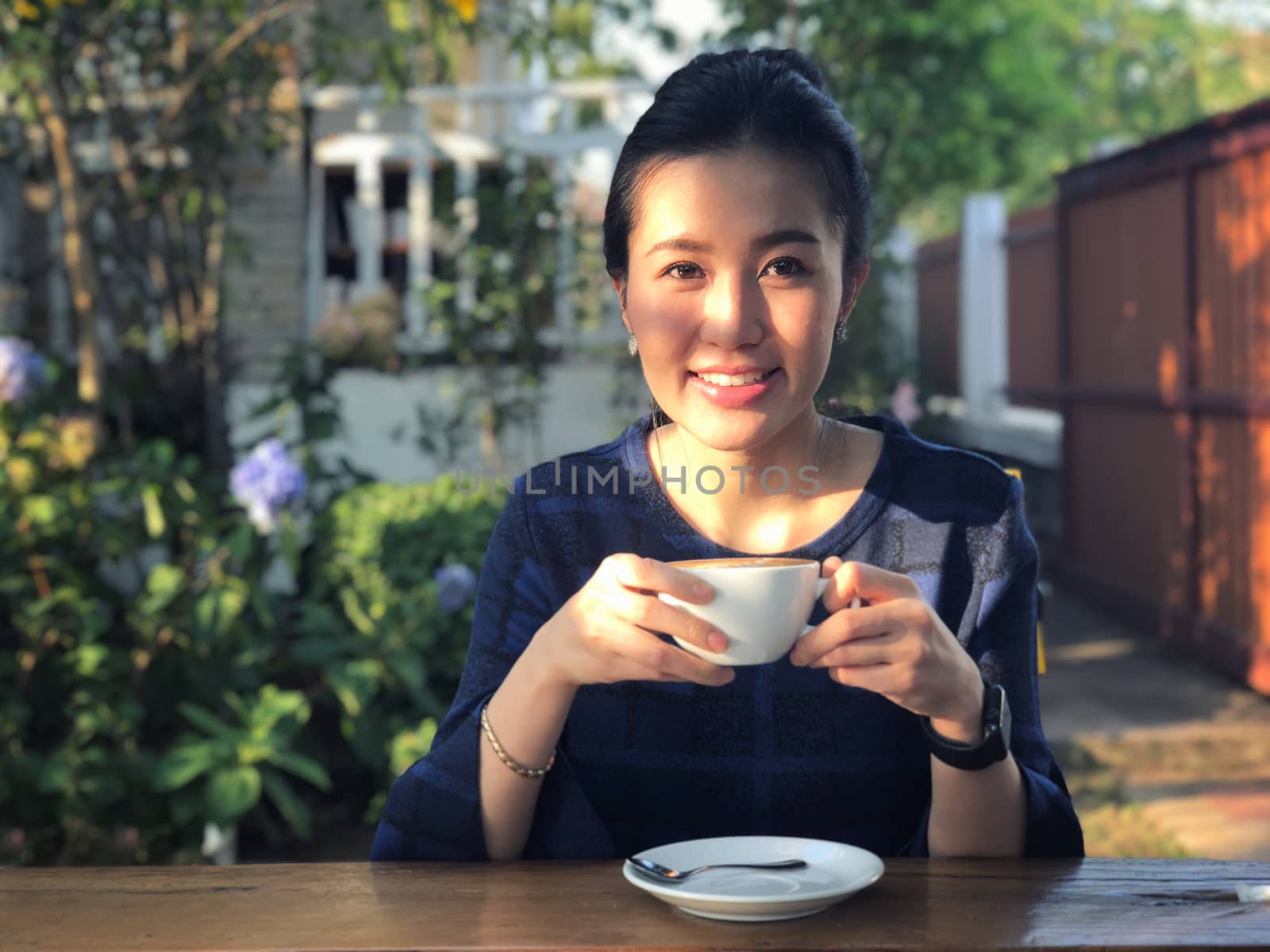 Young woman drinking coffee in in sunshine light enjoying her mo by Surasak