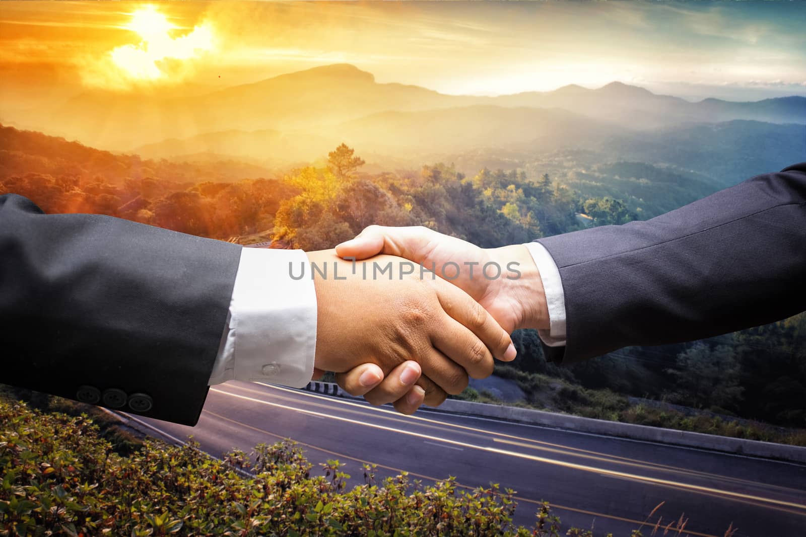 businessmen shaking hands on nature sunset mountain background by Surasak
