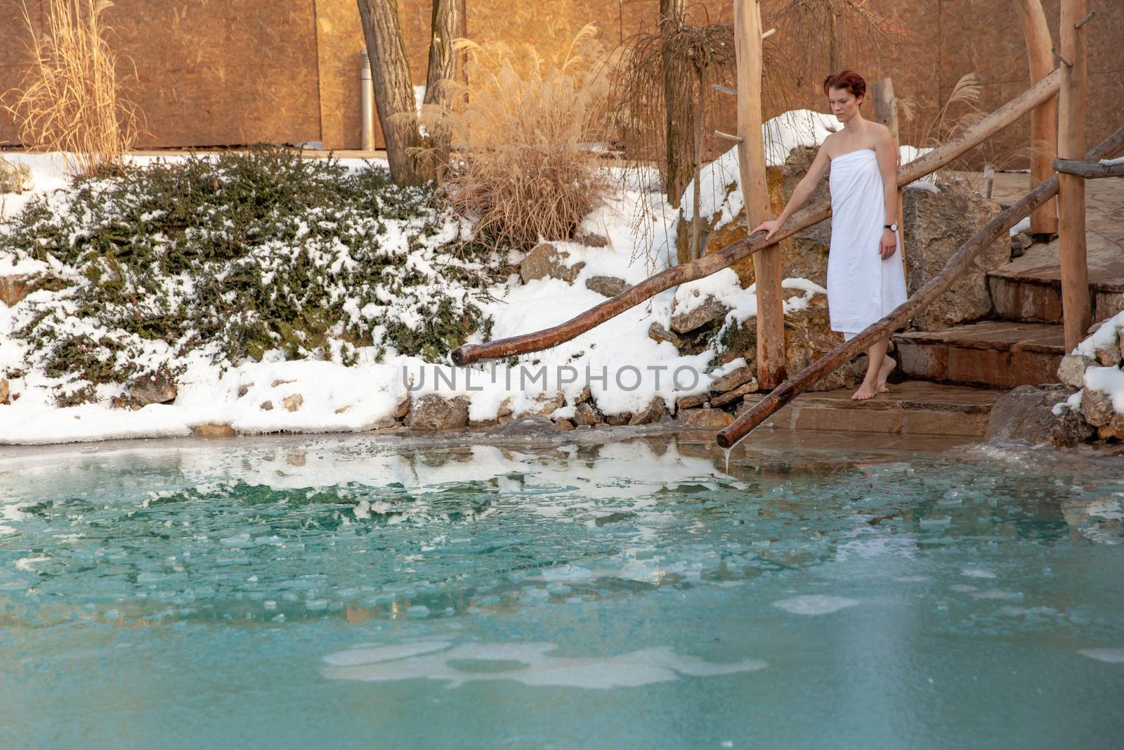 bathing young woman in a frozen lake after sauna.