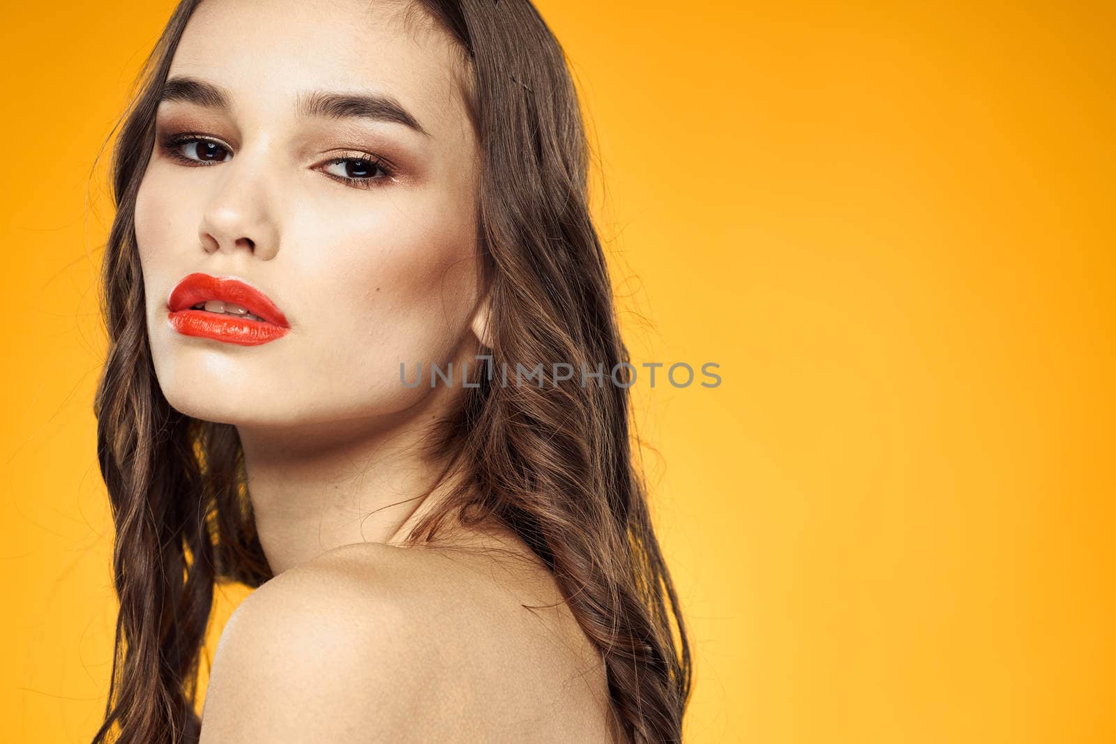 beautiful brunette red lips bare shoulders skin care yellow background. High quality photo