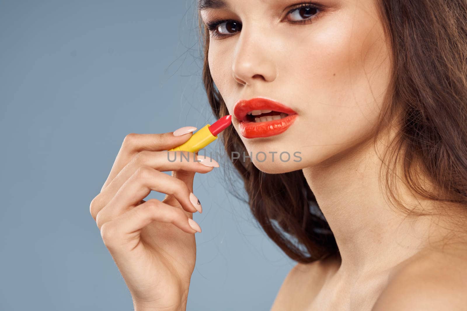 Woman with lipstick on a gray background brunette makeup with eye shadow on the eyelids. High quality photo