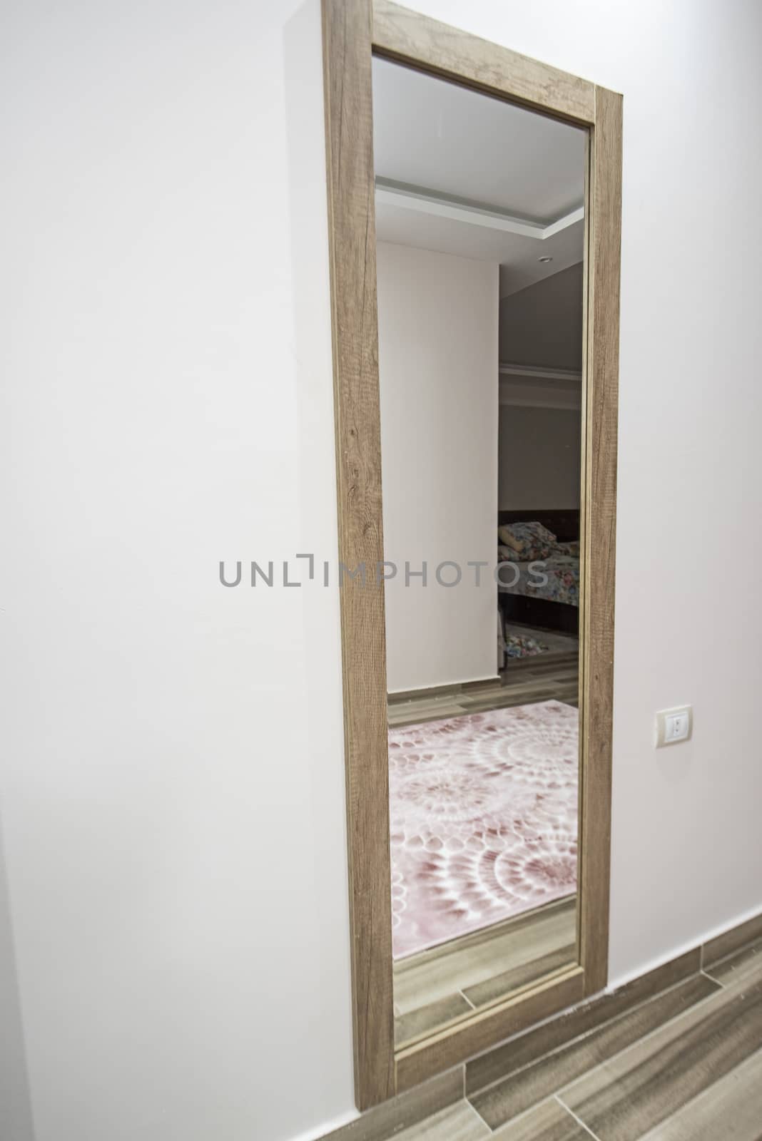 Tall full length mirror hanging on wall in bedroom of luxury home residence with reflection of bed
