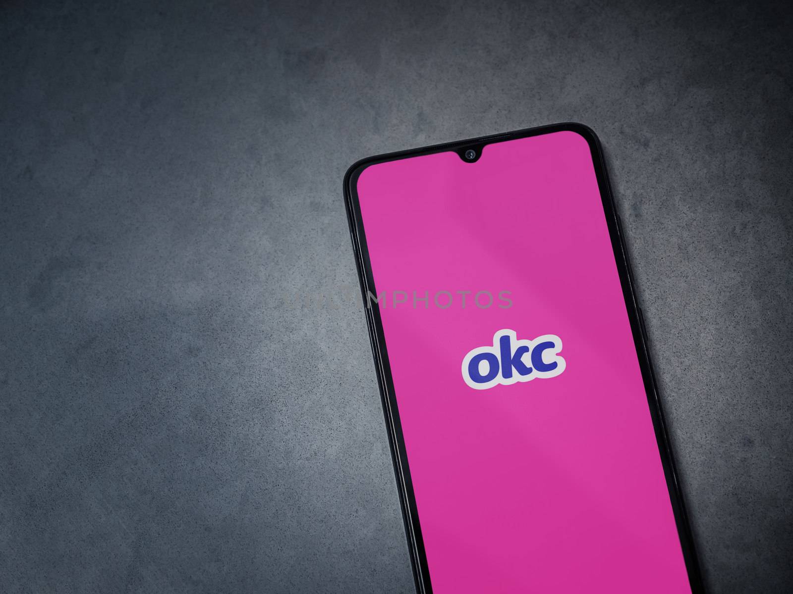 Lod, Israel - July 8, 2020: OkCupid app launch screen with logo on the display of a black mobile smartphone on dark marble stone background. Top view flat lay with copy space.