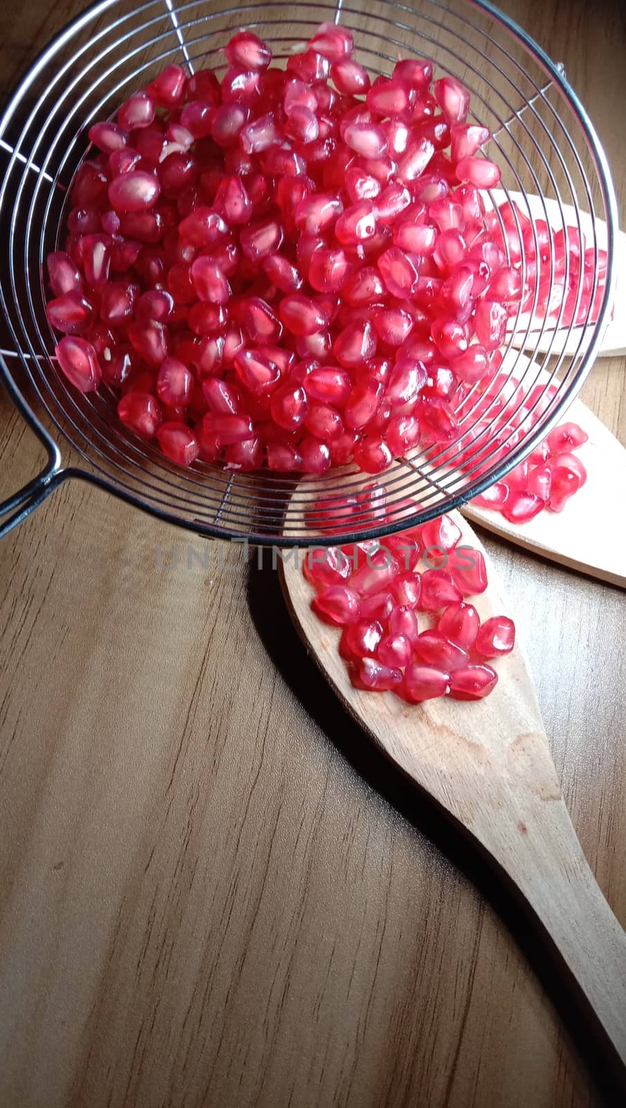 pomegranate seeds stock on net and wooden spoon