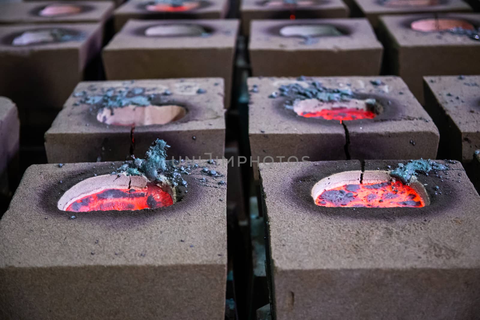 Cooling process of filled sand molds after steel casting, cracked during the process. Close-up view on rows on the factory floor.
