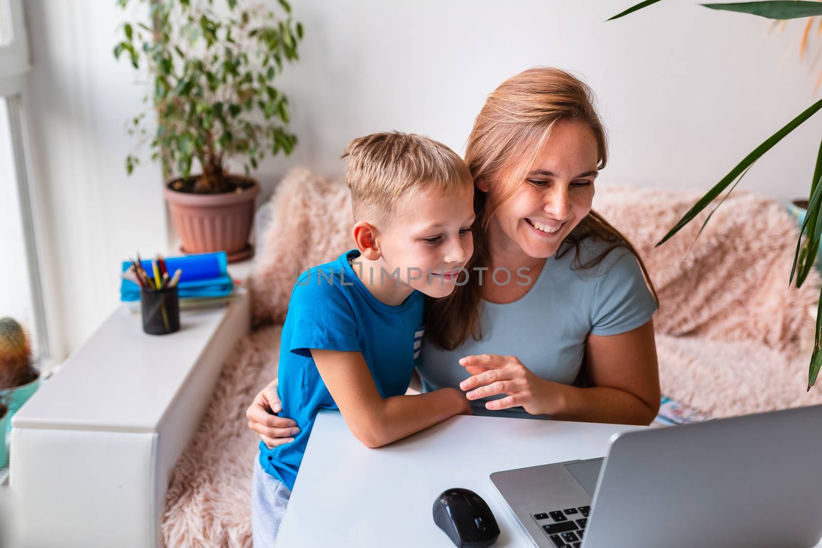 Mother with kid communicating online with relatives via video conferencing on laptop from home during quarantine. Distance communication concept during coronavirus pandemic