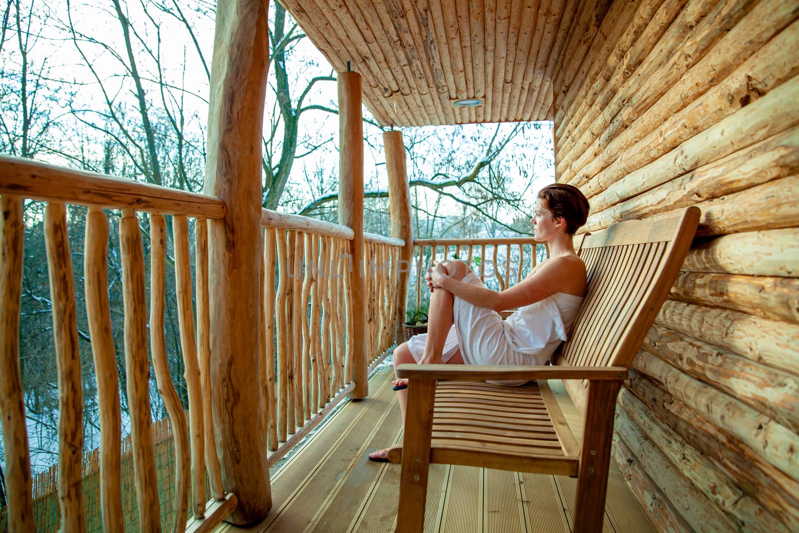 woman relaxes after sauna in a wooden log cabin in winter.