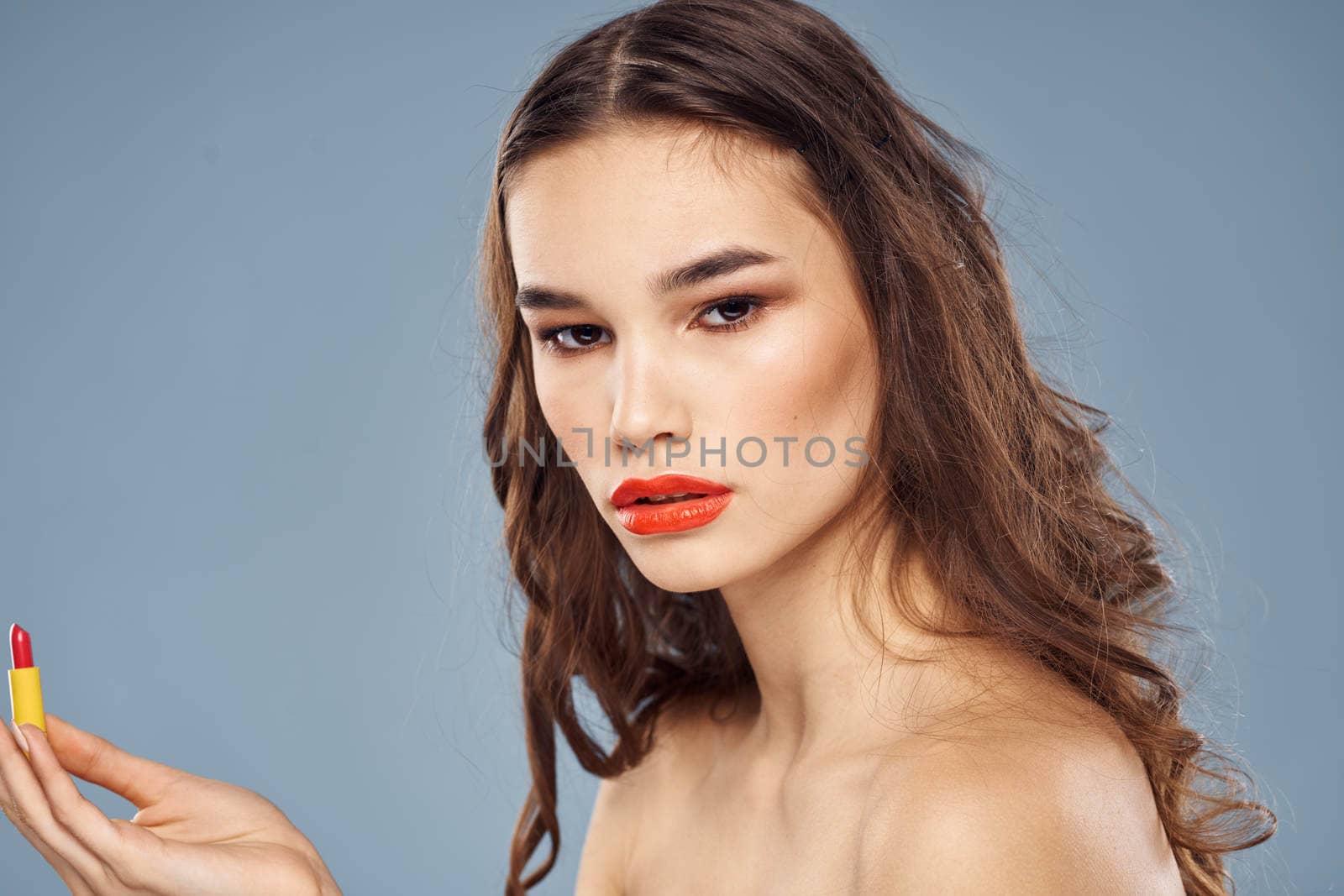 Woman with lipstick on a gray background brunette makeup with eye shadow on the eyelids. High quality photo