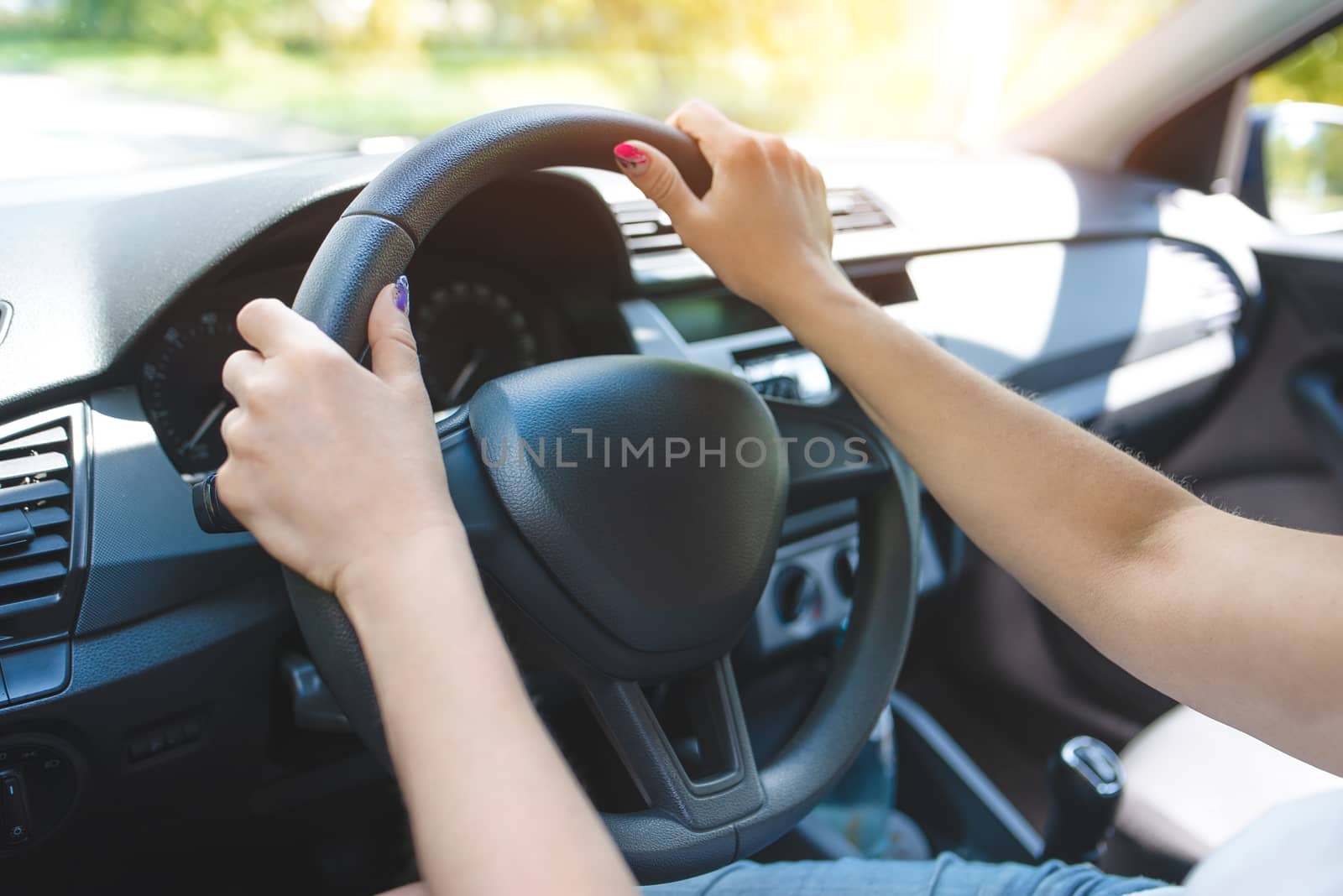 Close up woman hands keeping steering wheel while sitting in modern interior of vehicle. Girl driving car at street concept