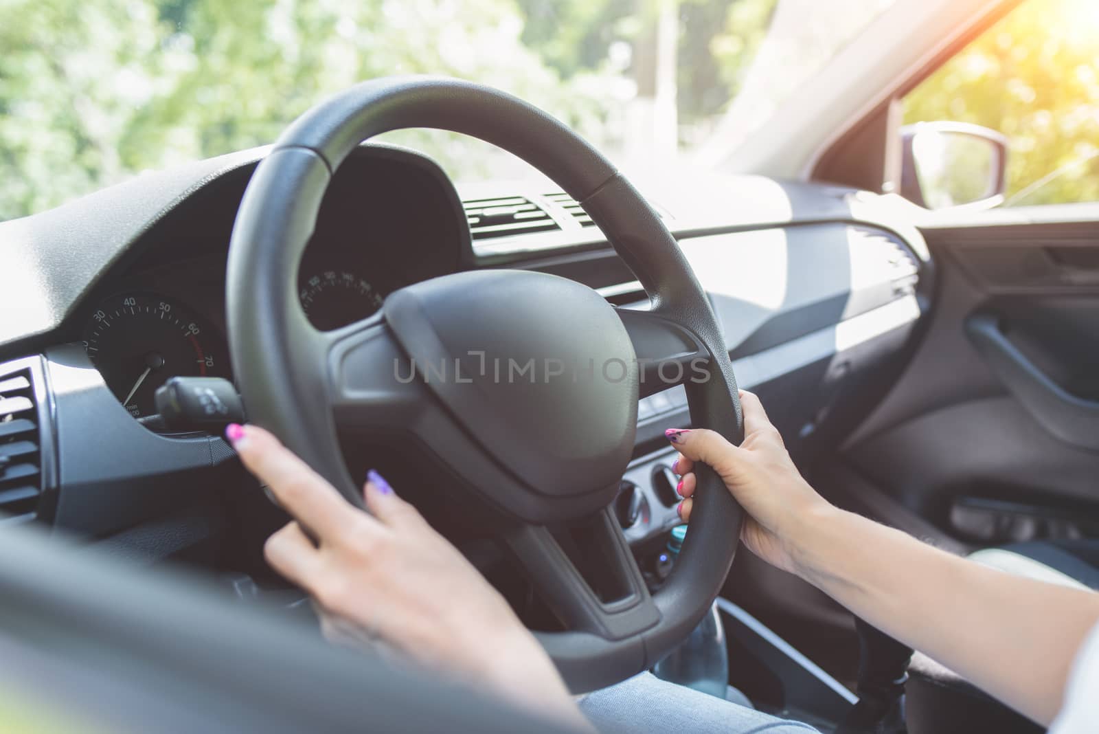 Close up woman hands keeping steering wheel while sitting in modern interior of vehicle. Girl driving car at street concept