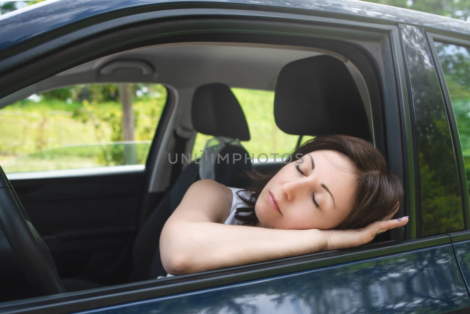 Very tired woman sleeping on a car window.driving safety concept