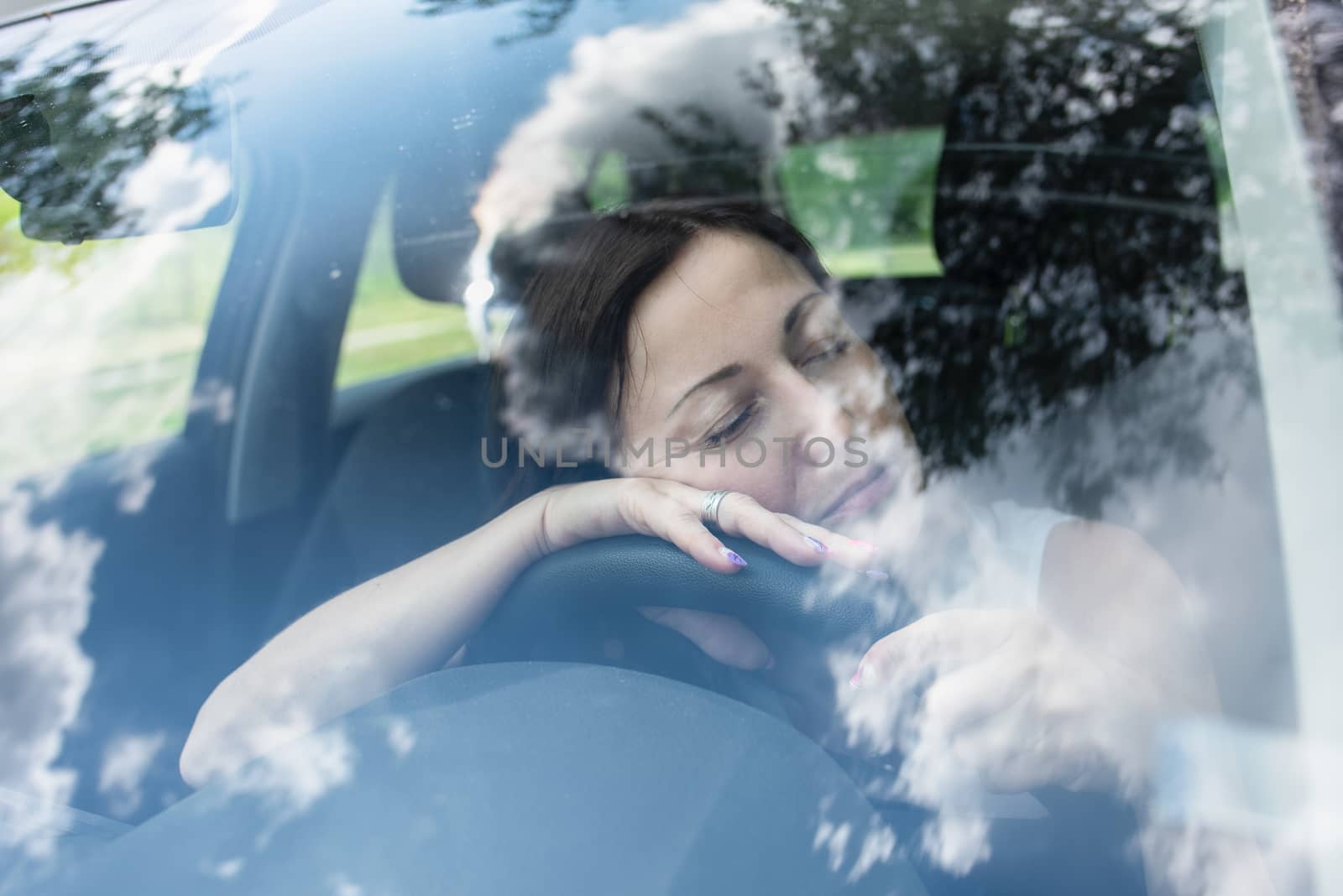 Young female driver at the wheel of her car, very tired, falling asleep while driving in a potentially dangerous situation - Road safety concept