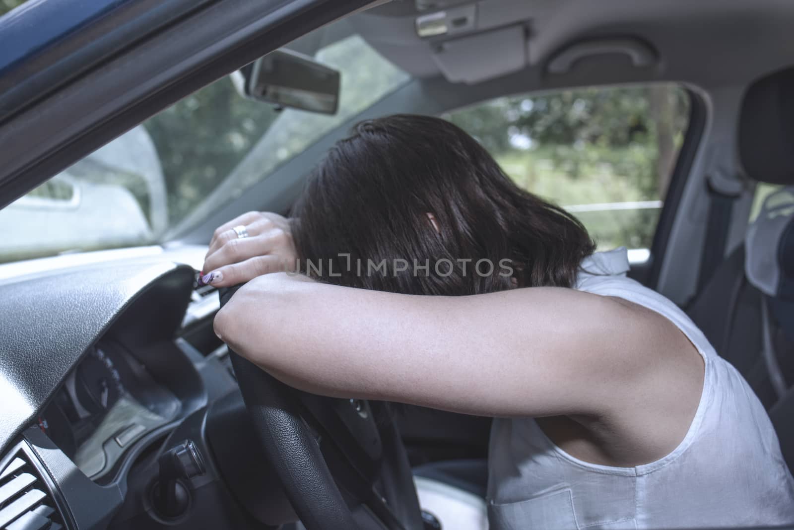 Young female driver at the wheel of her car, super tired, falling asleep while driving in a potentially dangerous situation - Road safety concept