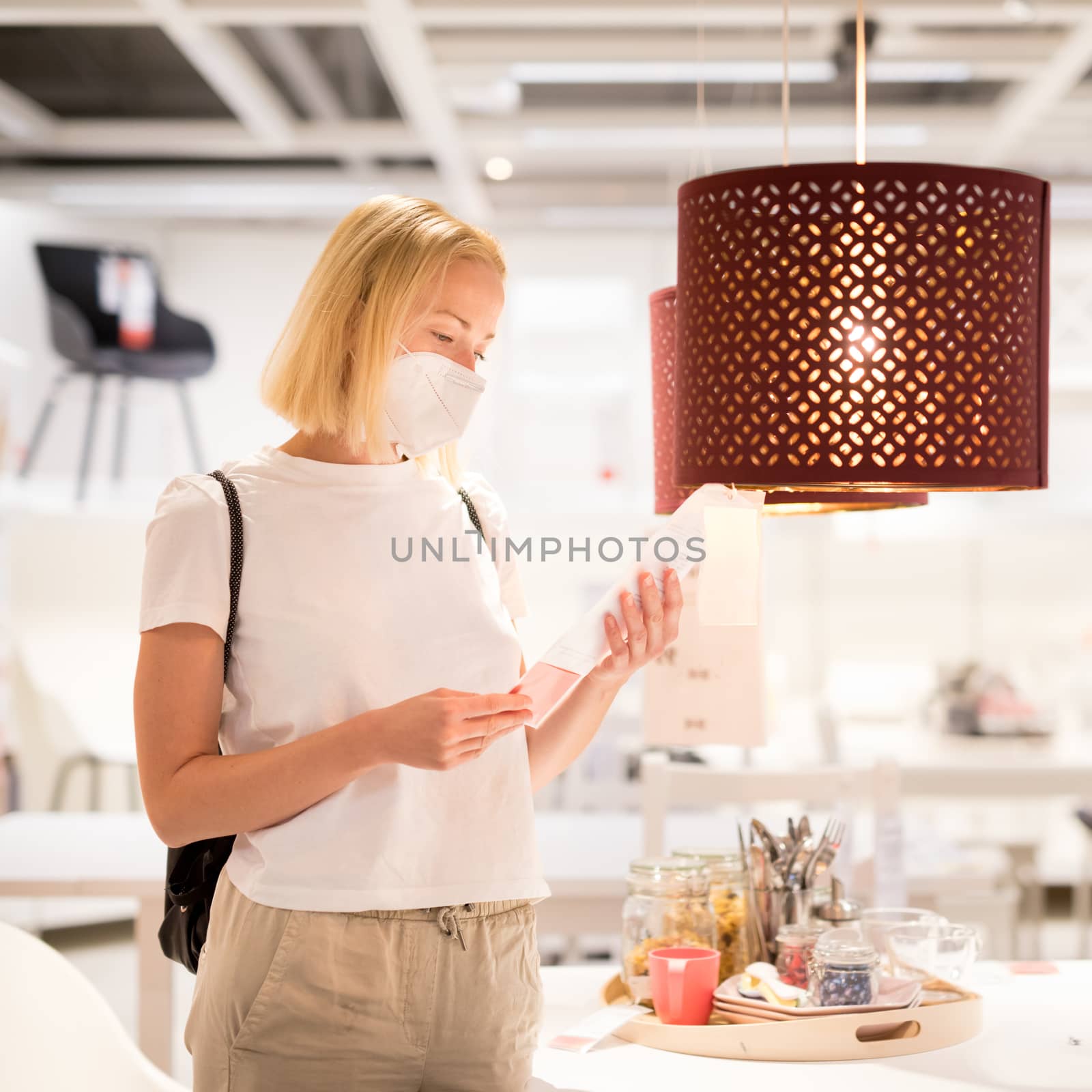 New normal during covid epidemic. Caucasian woman shopping at retail furniture and home accessories store wearing protective medical face mask to prevent spreading of corona virus by kasto