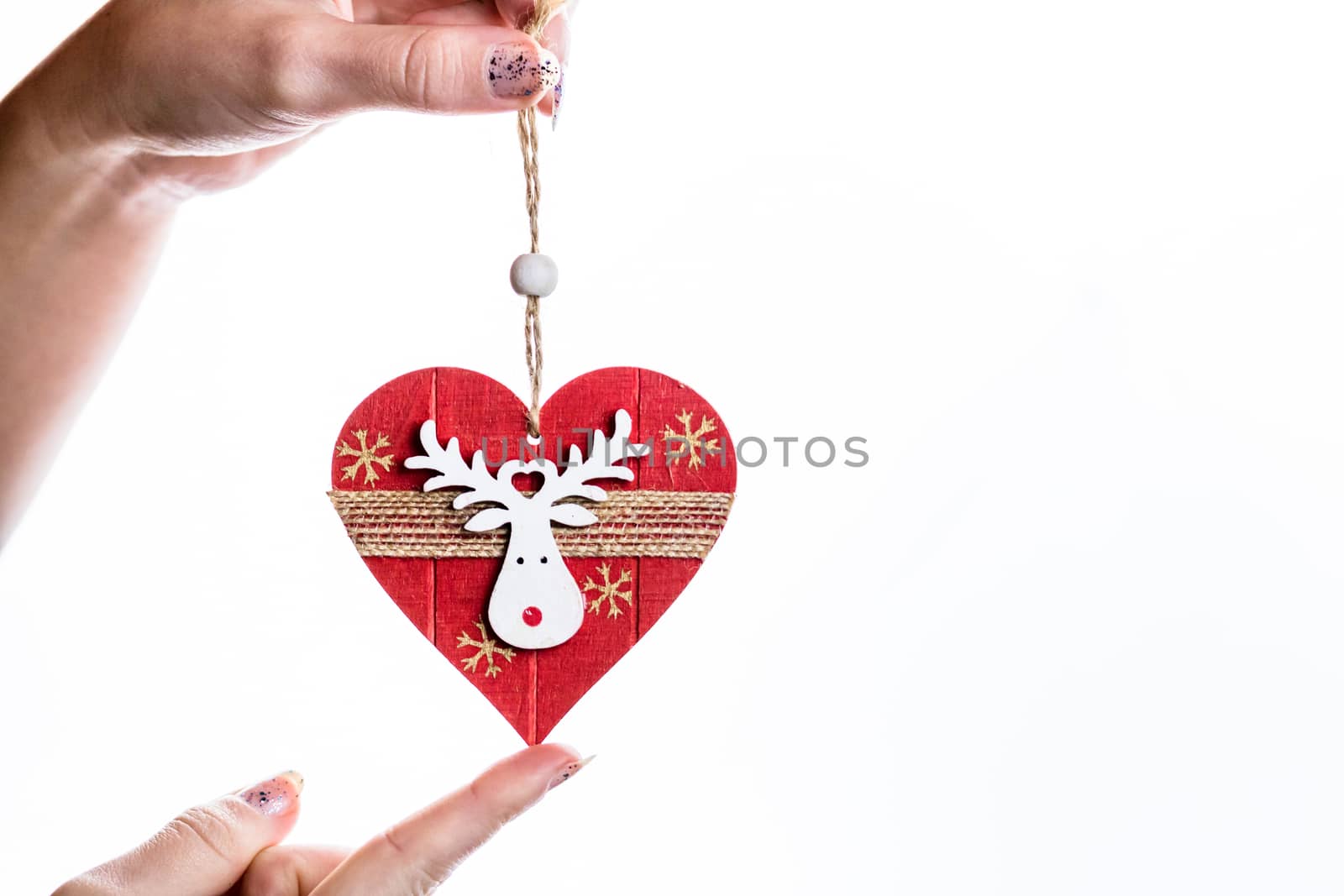 Hand holding heart shaped Christmas decoration isolated on white.