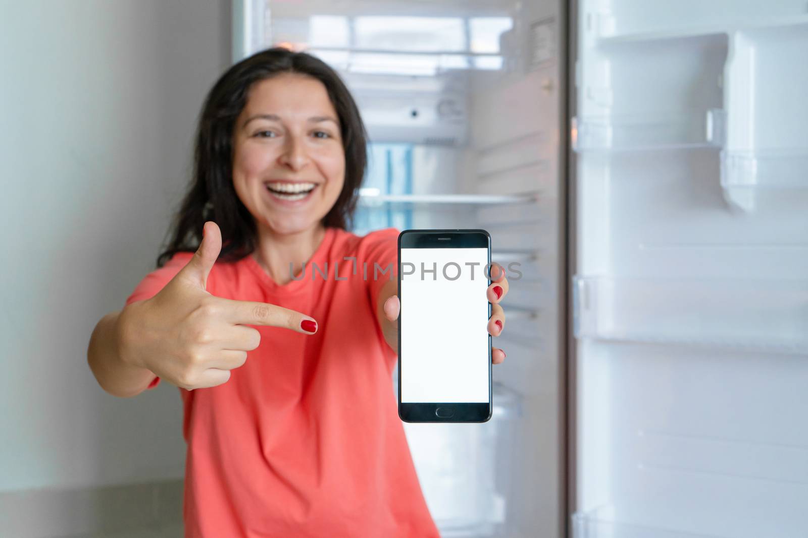 A girl orders food using a smartphone. Empty refrigerator with no food. Food delivery service advertisement.