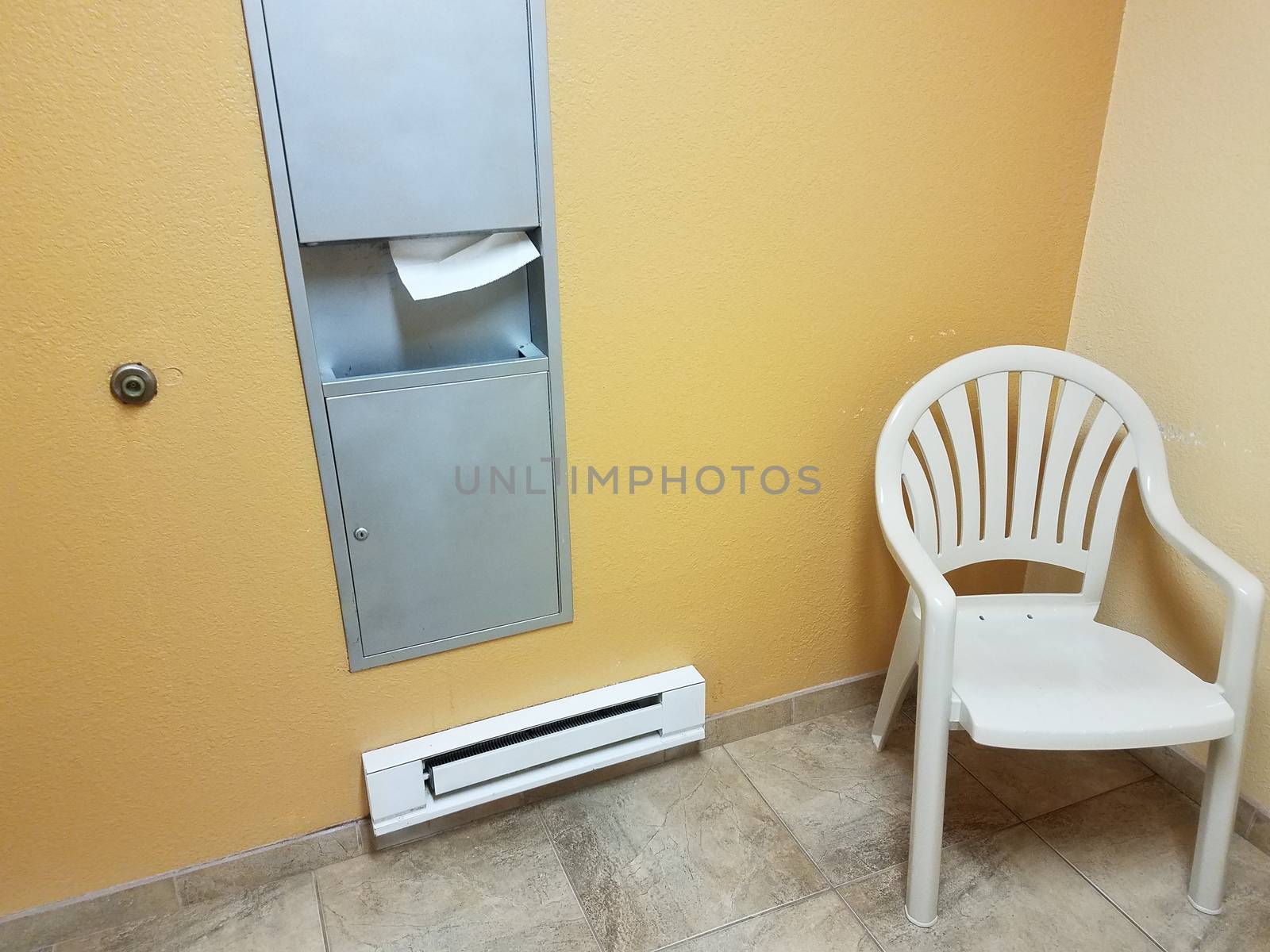 heater with paper towel dispenser and chair in bathroom or restroom