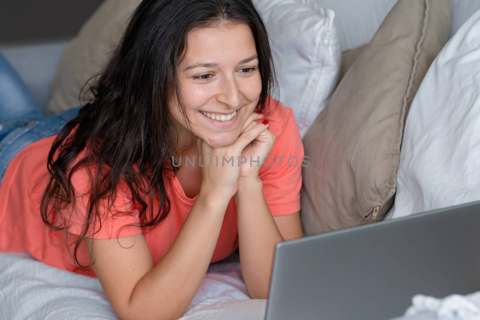 Girl lying on the couch rejoices looking at the laptop. Smiles, good mood, emotion of joy.