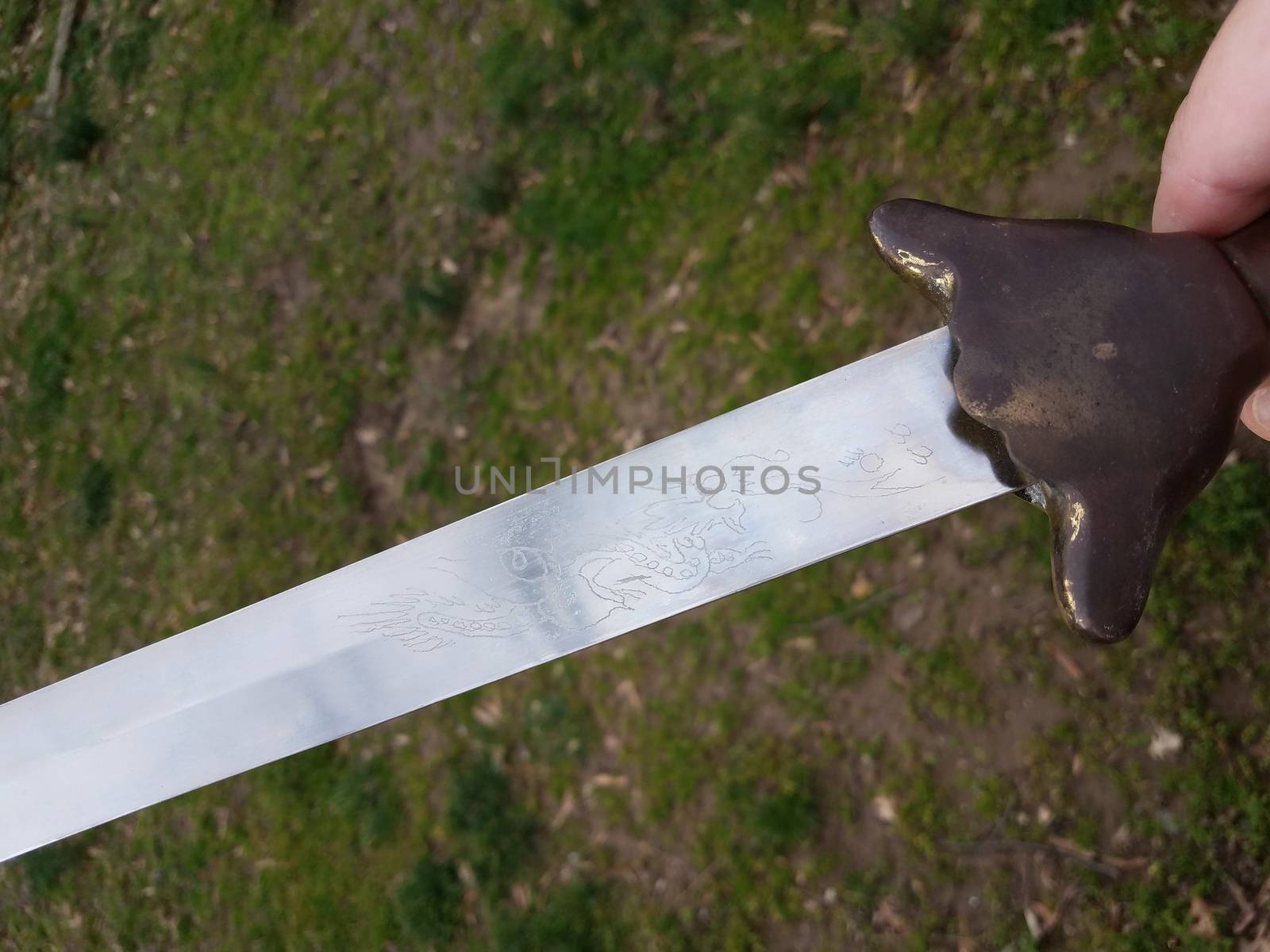 hand holding metal Chinese sword with copper handle by stockphotofan1