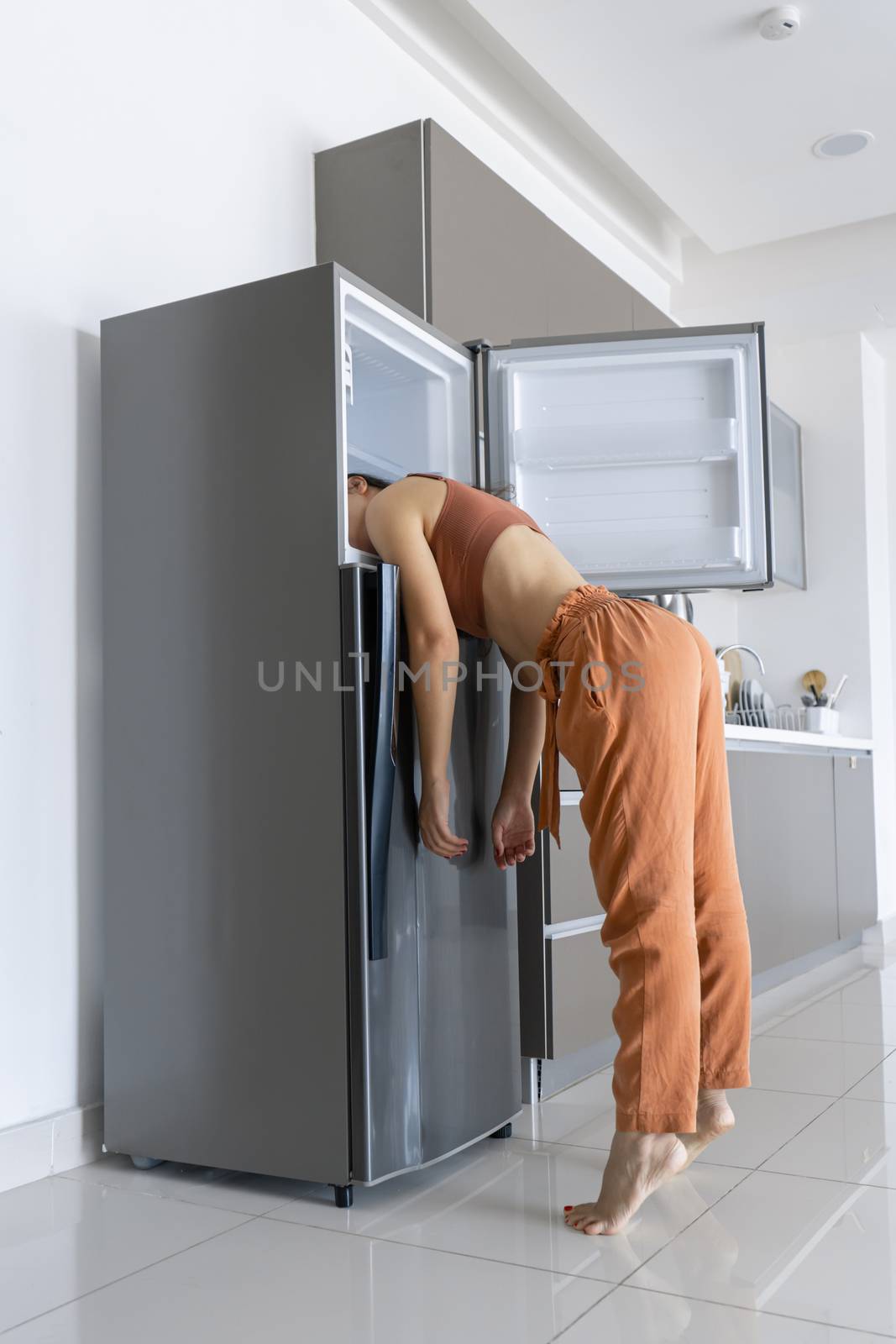 On a hot day, the girl cools with his head in the refrigerator. Broken air conditioner.