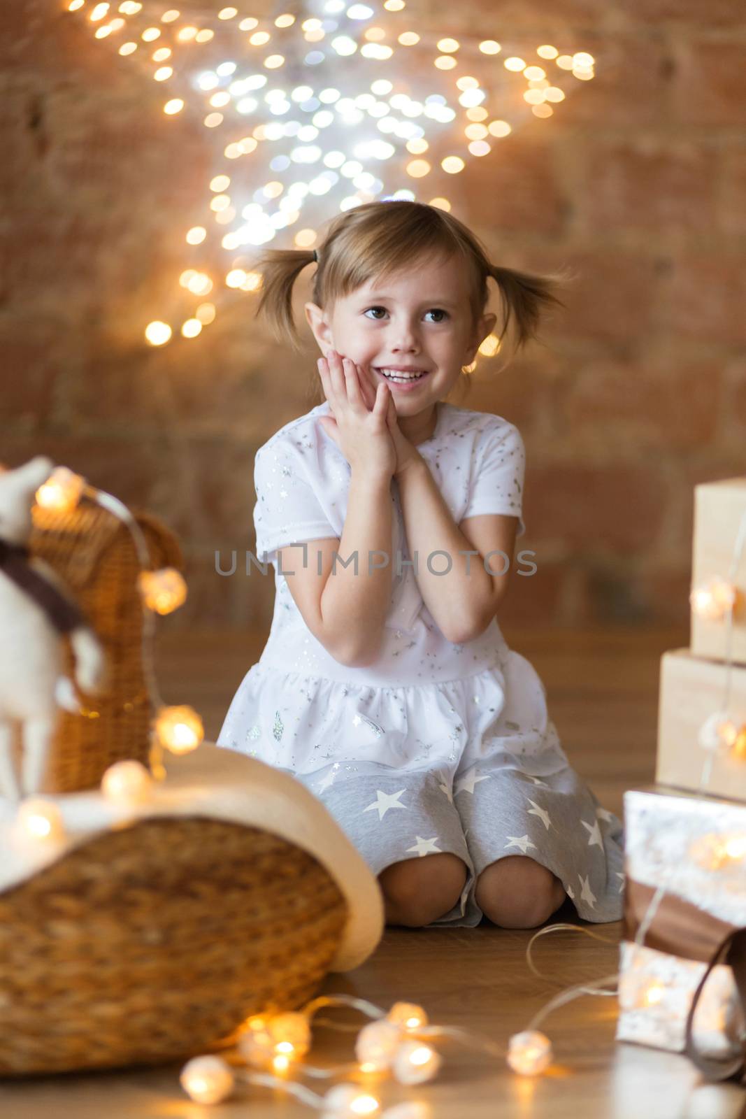 .Adorable little girl sitting on the floor among the new year garlands.