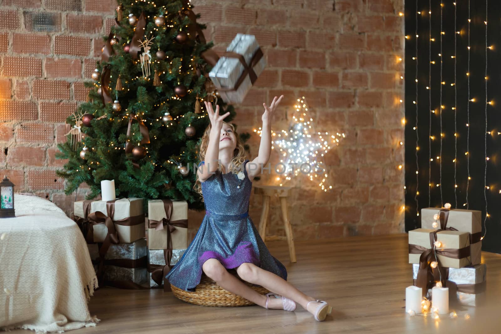 .Adorable little girl in a luxurious dress throws up a gift box near the tree by galinasharapova