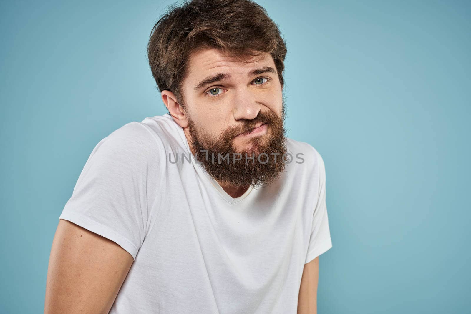 Man in white t-shirt emotions facial expression cropped view studio blue background lifestyle. High quality photo