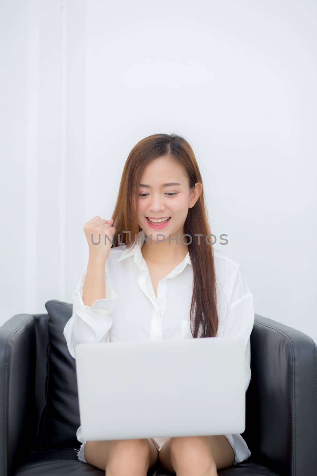 Beautiful of portrait happy young asian woman using laptop work with success on chair in the home, girl and notebook shopping online with glad, communication concept.