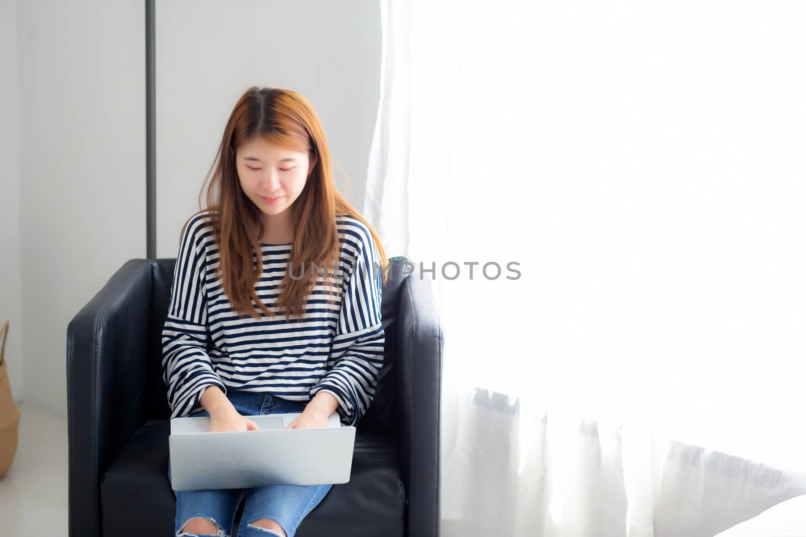 Beautiful of portrait young asian woman using laptop computer  for leisure on chair at living room, girl working online with notebook freelance, communication business concept.