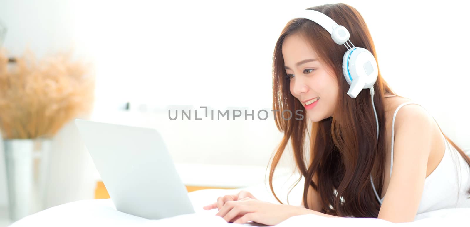 Banner website beautiful asian young woman relax listening to music with headphone and laptop online internet on vacation in bedroom, cheerful of asia girl leisure, lifestyle concept.