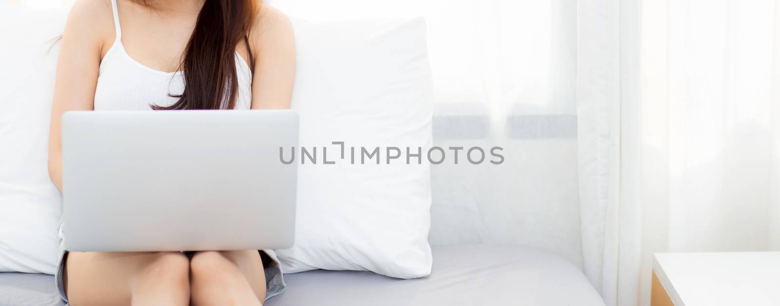 Banner website beautiful young asian woman using laptop for leisure on bedroom, girl working online with notebook freelance, technology and business concept.