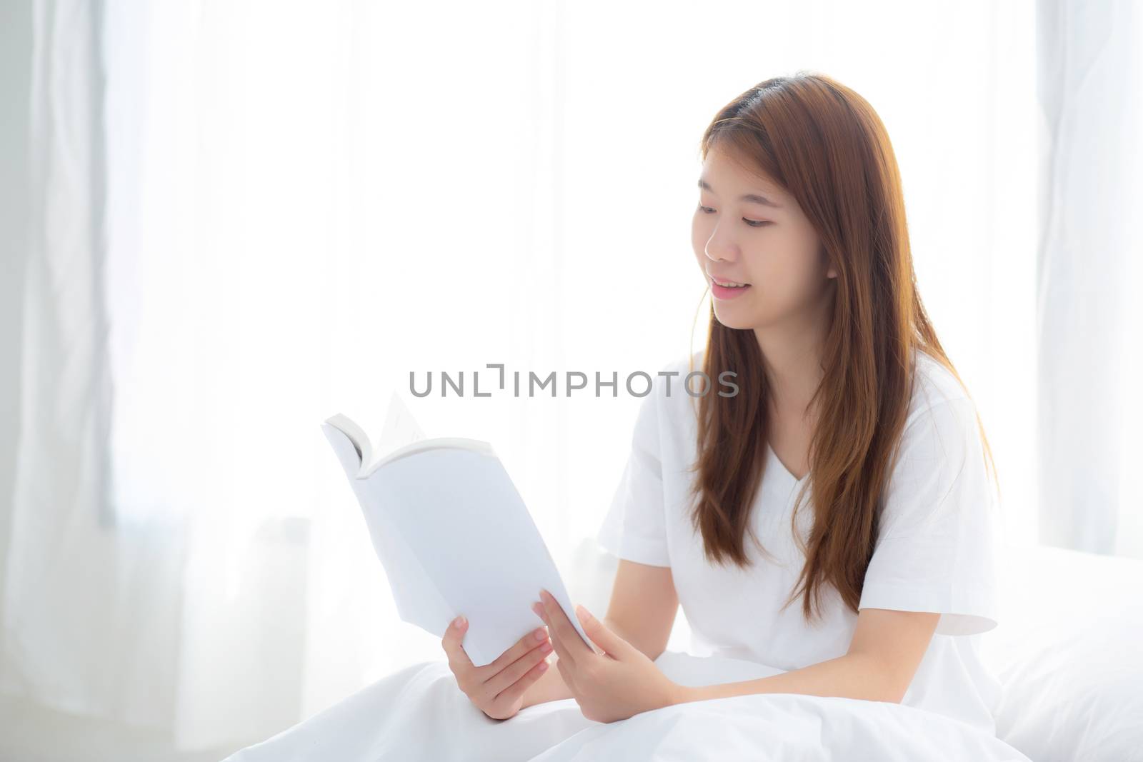Beautiful of portrait young asian woman relax sitting reading book on bedroom at home, girl study literature, education and llifestyle concept.