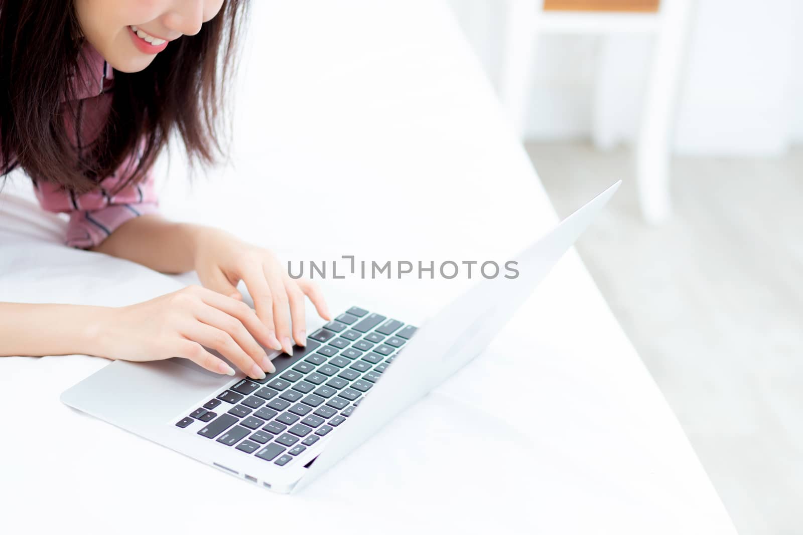 Beautiful asian young woman lying on bed using laptop at bedroom for leisure and relax, freelance with girl working notebook, communication concept.