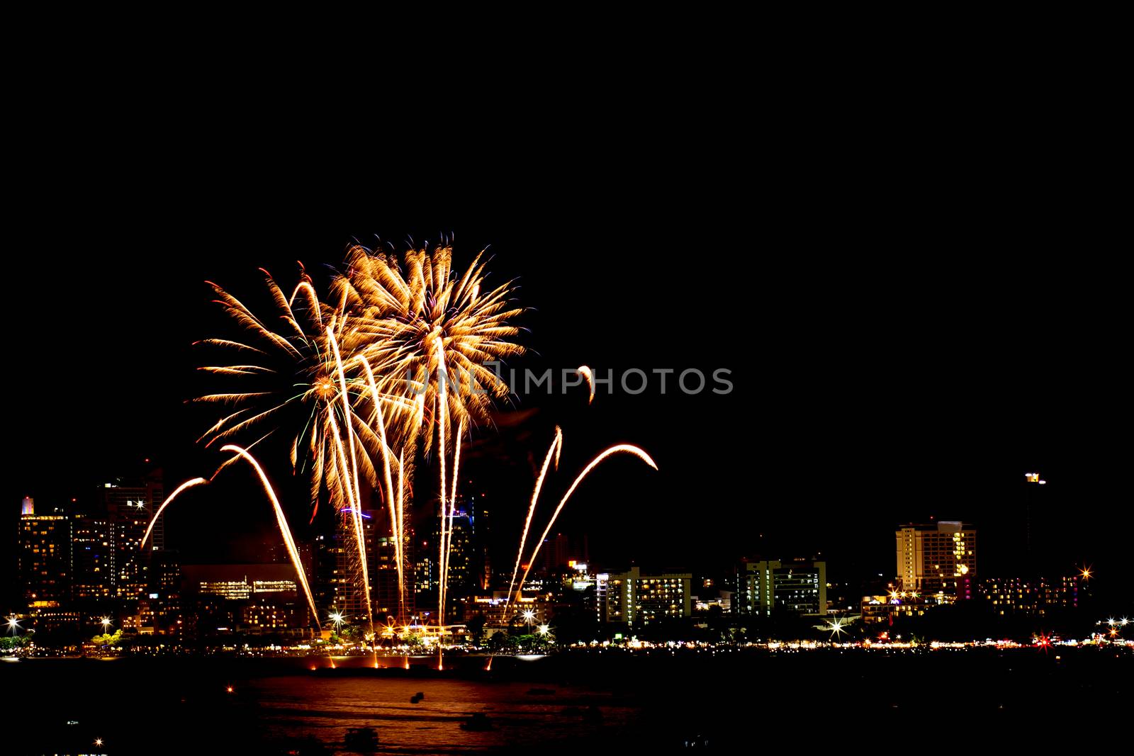 Many flashing fireworks with night cityscape background celebrate New Year.
