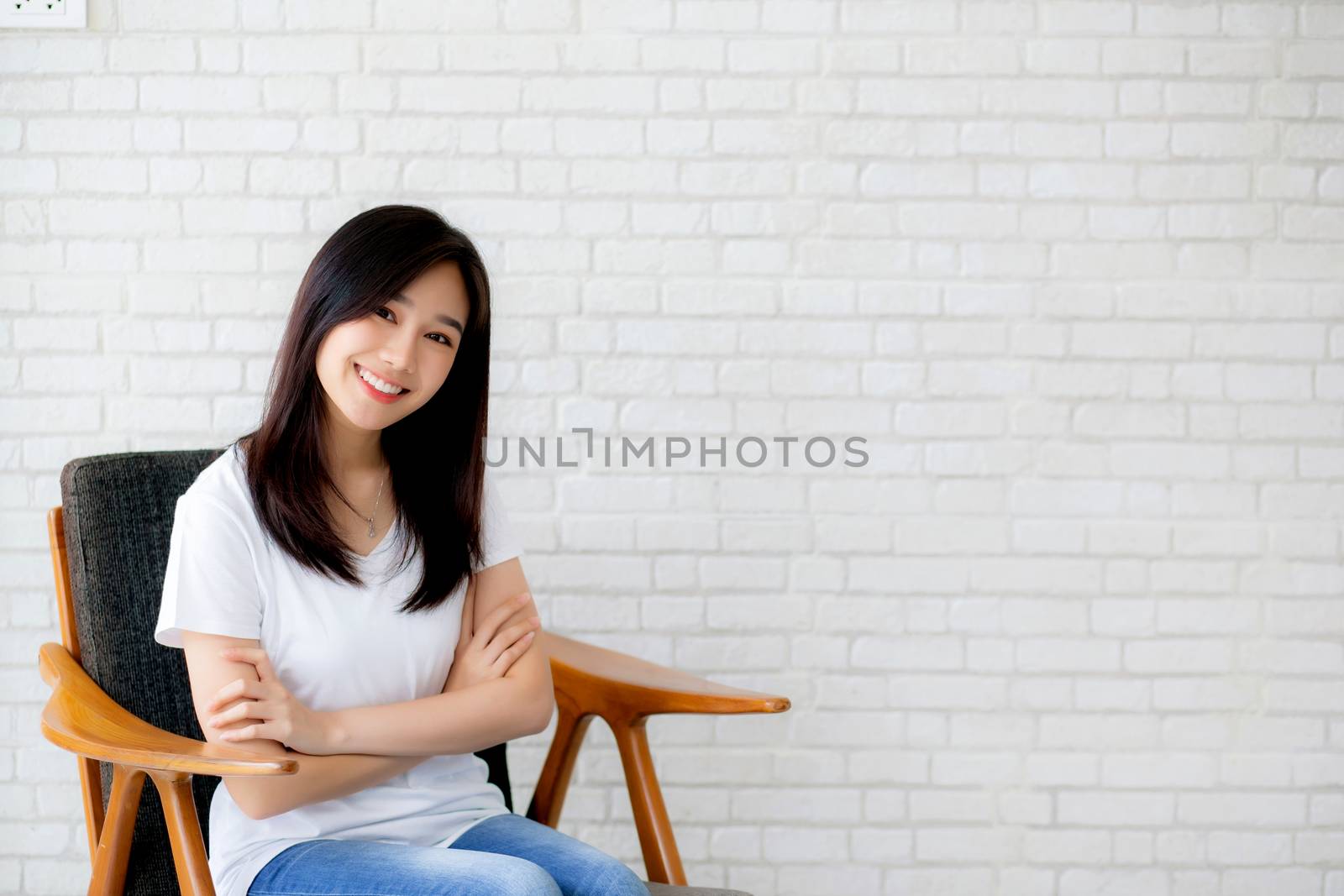 Portrait of beautiful young asian woman happiness sitting on chair on gray cement texture grunge wall brick background, businesswoman is a smiling on concrete, business people concept.