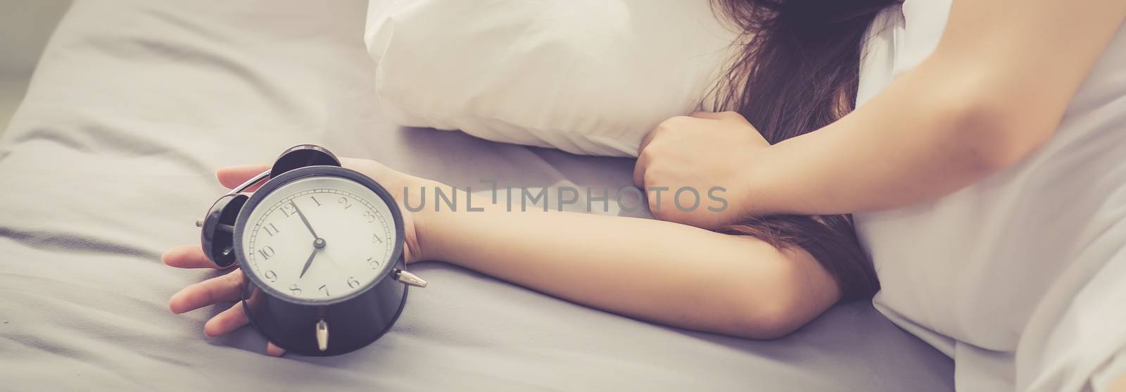 Banner website closeup asian young woman turn off alarm clock in by nnudoo