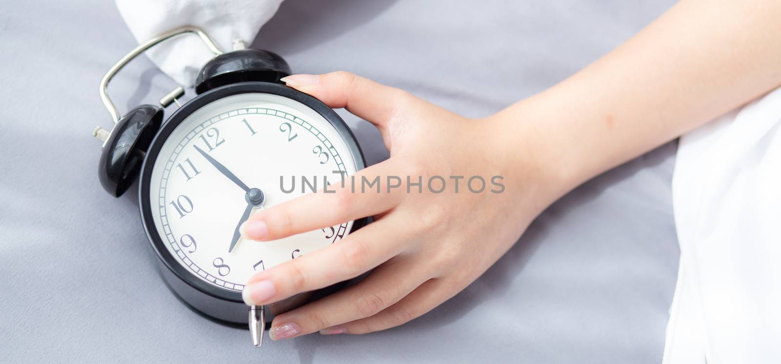 Banner website closeup asian young woman turn off alarm clock in by nnudoo