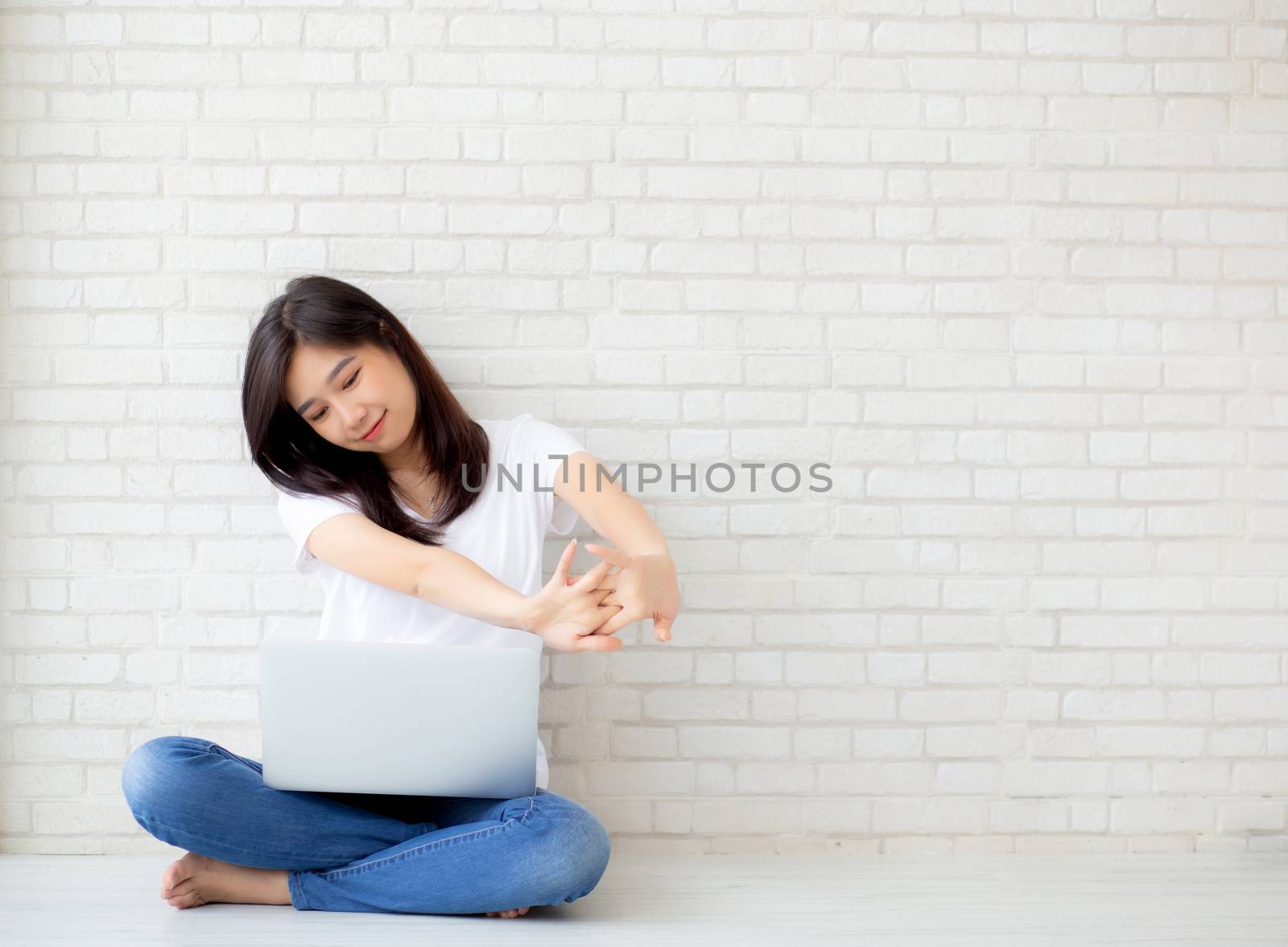 Beautiful portrait young asian woman sitting with laptop stretch and exercise relax after work success on cement concrete background, modern office with copy space, freelance business concept.