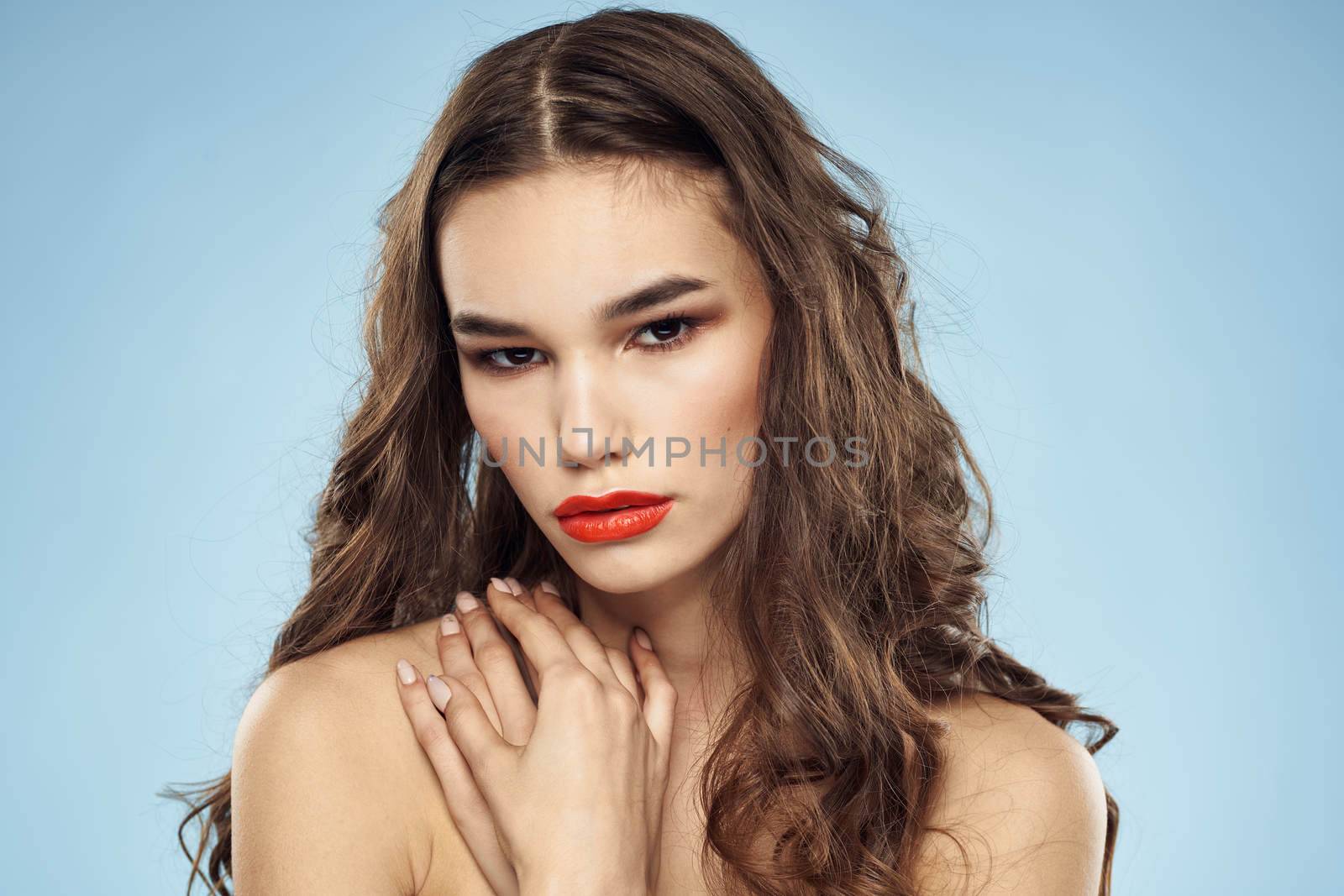 Elegant brunette fashionable hairstyle bright makeup naked shoulders close-up blue background. High quality photo