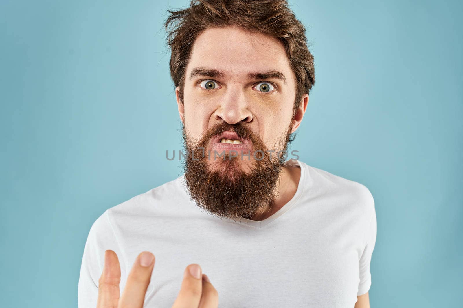 Man with disgruntled facial expression gesturing with hands studio lifestyle blue background by SHOTPRIME