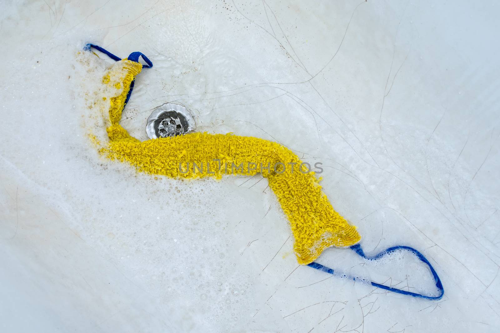 The washcloth lies in the bathtub in foam surrounded by water