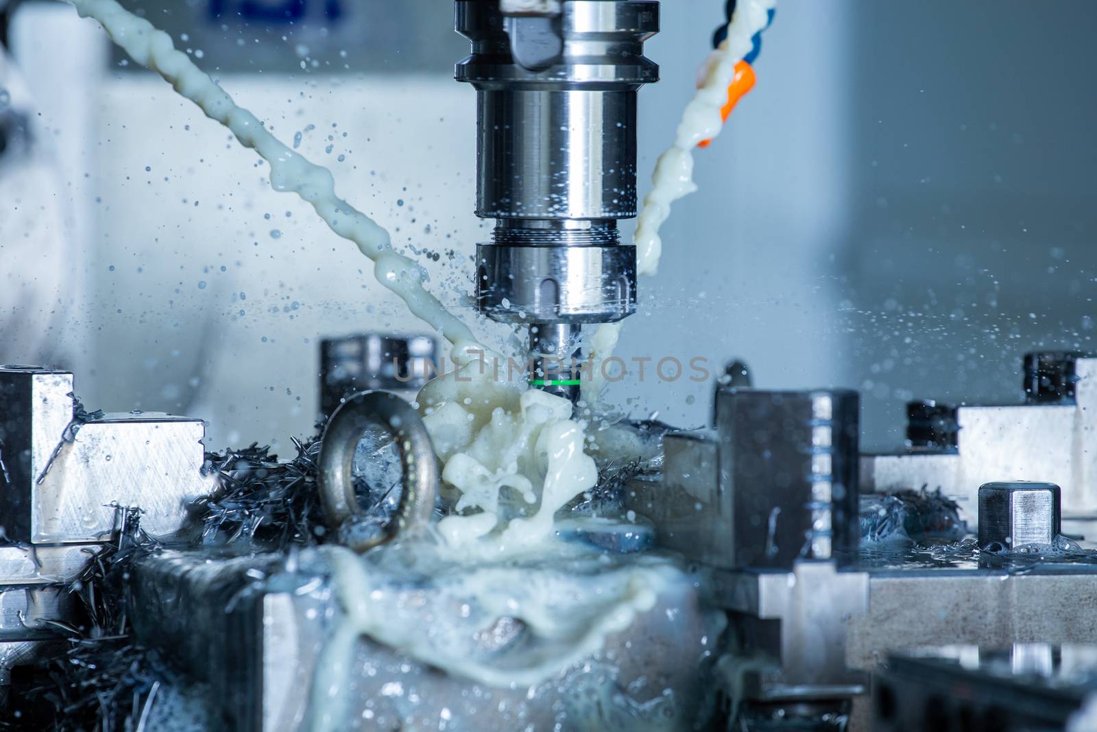 A process of vertical cnc steel milling with external water coolant streams, splashes and a lot of metal chips. Fast shutter speed for motion freezing.