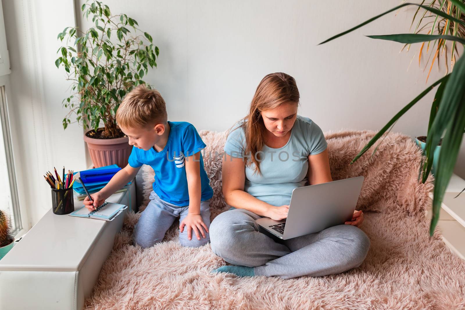 Mother with kid trying to work from home during quarantine. Stay at home, work from home concept during coronavirus pandemic