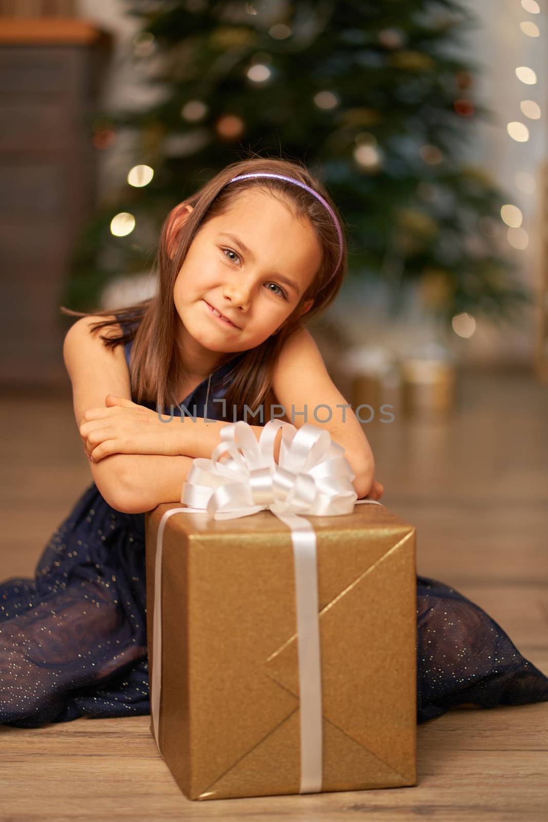 Happy childhood, Christmas magic fairy tale. Little girl dreams before opening Santa's present for Christmas.