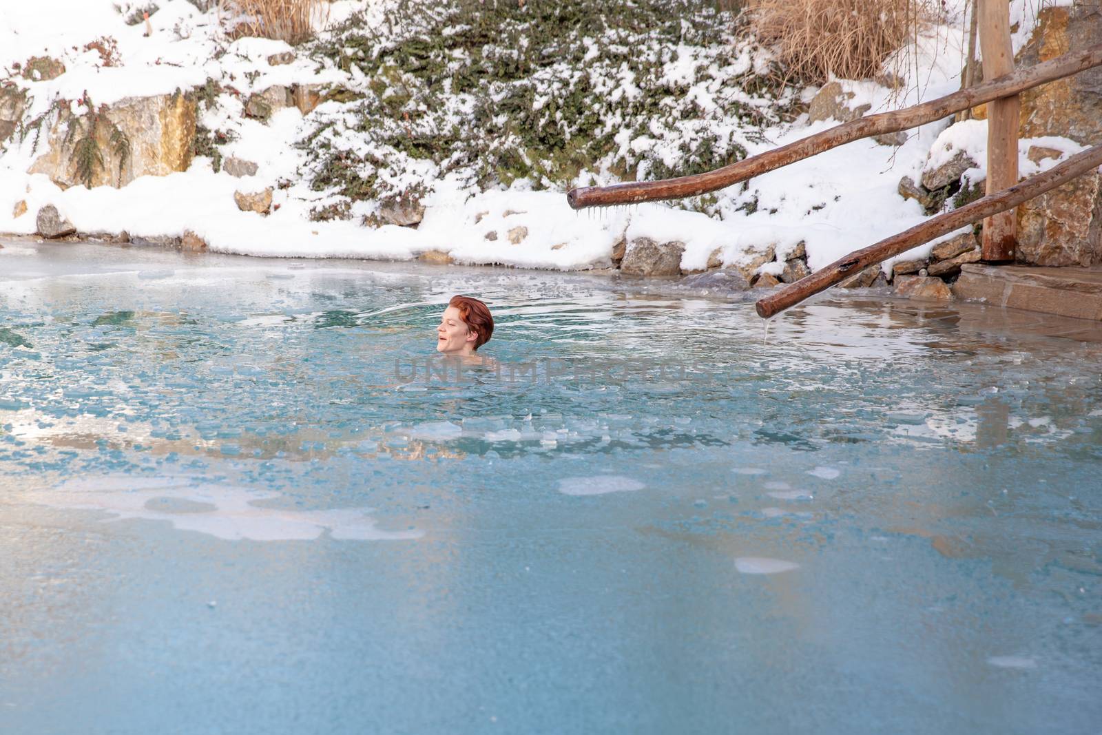 bathing young woman in a frozen lake after sauna by Edophoto