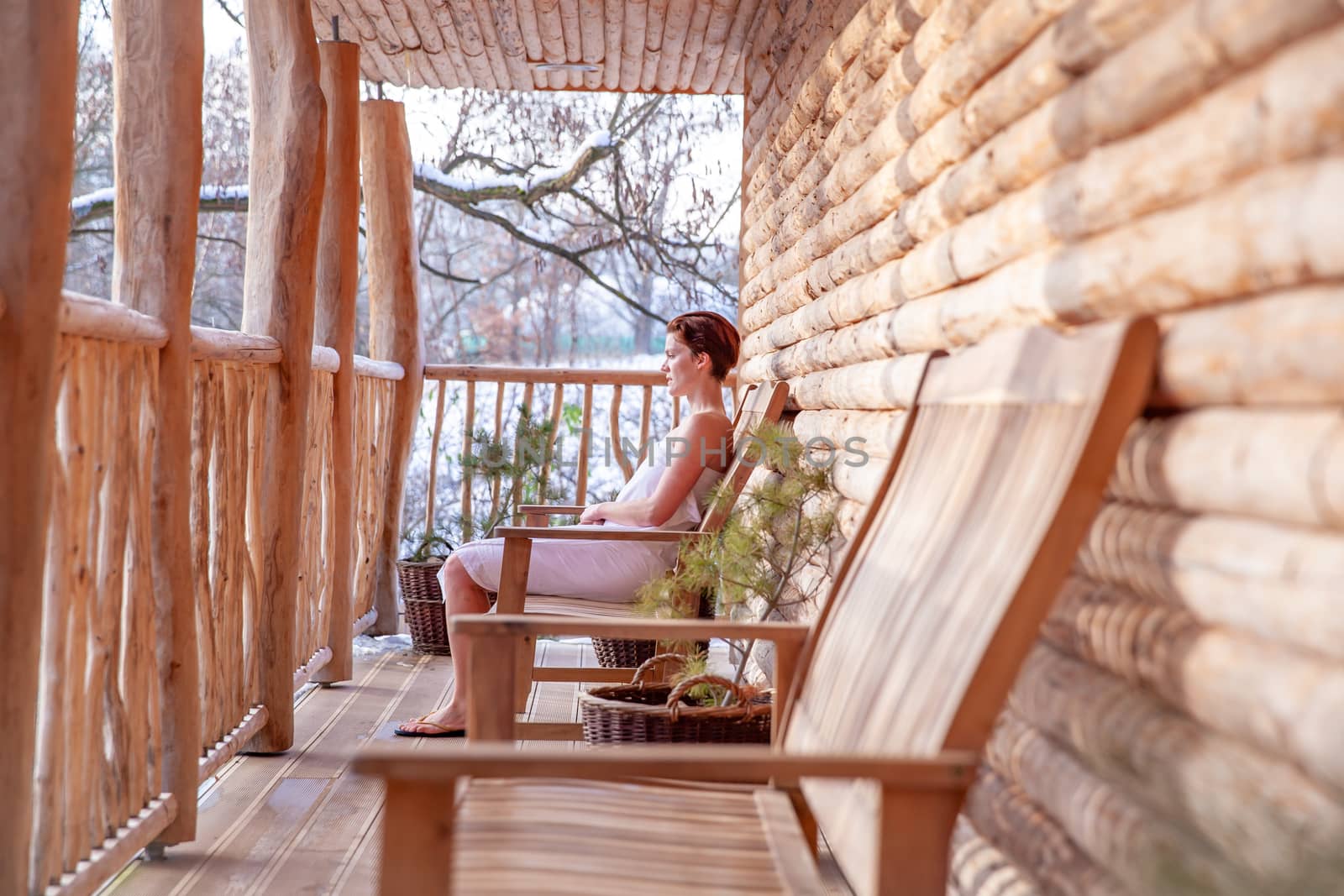 woman relaxes after sauna in a wooden log cabin in winter.