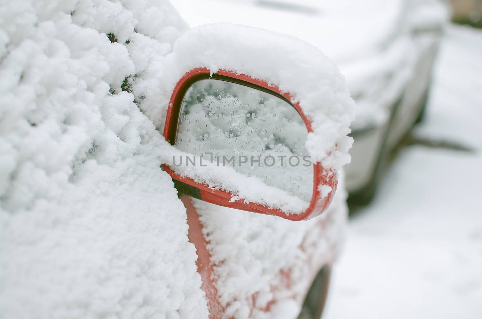 Mirror of a car covered in snow during snowstorm. Snowstorm forecast. Winter in the city. Negative temperature and car preparation for winter travel