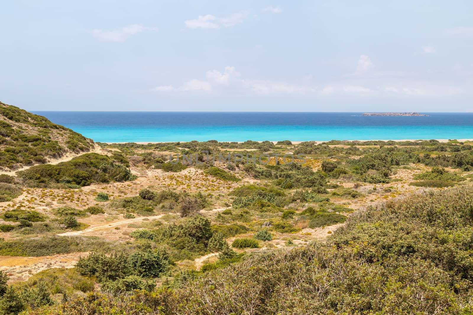 Landscape on the west coast of Rhodes island, Greece near Kattavia with green vegetation in the foreground and turqouise water in the background on a sunny day